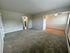 Inviting living room with plush carpeting, adjacent to a cozy dining area with a ceiling fan.