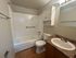 Modern bathroom featuring a sleek white tub with safety grab bars, elegant vanity with marble countertop, and ample storage space in a neutral palette.