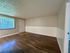 Inviting living space with sleek wood flooring, large window with blinds, and modern entry door.