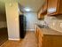 Modern kitchen featuring granite countertops, dual sink, wooden cabinetry, and sleek black refrigerator with tile flooring.