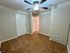 Bright room with neutral walls, a ceiling fan, tiled flooring, and a door leading to a hallway.