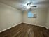 Inviting room with modern wood flooring, neutral walls, a bright ceiling fan, and efficient window AC unit.