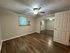 Bright room with elegant wood flooring, mirrored closet doors, and a modern ceiling fan, offering a comfortable and stylish living space.