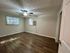 Bright and inviting room with sleek hardwood flooring, a ceiling fan for comfort, and natural light filtering through large windows.