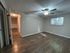Inviting empty room with warm wood flooring, ample natural light from a window with blinds, and a stylish ceiling fan.