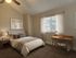 Inviting bedroom with elegant decor, featuring a cozy bed, soft beige tones, and a stylish wooden desk next to a luminous window.