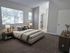 Inviting bedroom featuring a plush bed, elegant decor, and abundant natural light through large windows.