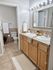 Elegant bathroom featuring a double sink vanity with warm wood cabinets, a large mirror with bright lighting, and modern decor for a refreshing ambiance.