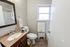 Inviting bathroom with elegant wooden vanity, cozy decor, and natural light from a classic window.