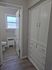 Bright hallway showcasing modern hardwood flooring, ample built-in storage, and a cozy bathroom entrance.