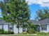 Charming single-story home with blue siding, lush landscaping, and a welcoming front porch under a clear blue sky.