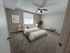 Elegant bedroom with a plush carpet, cozy bed, modern decor, and a large window letting in natural light.