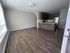 Modern open-concept living area with sleek hardwood floors and a stylish kitchen featuring dark cabinetry and stainless steel appliances.