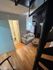 Inviting living space with a cozy sofa, adjacent bathroom, and a compact kitchen featuring modern appliances and wooden flooring.
