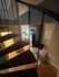 Elegant loft apartment view featuring a stylish spiral staircase leading to an open living area with warm wood flooring, modern kitchen, and cozy seating space.