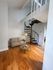 Chic living room with modern spiral staircase, cozy sofa, and elegant hardwood floors, creating a stylish and welcoming atmosphere.