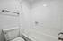 Pristine modern bathroom with white tiled walls and a sleek bathtub, offering a clean and inviting atmosphere.