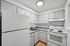 Bright, compact kitchen with white cabinetry, modern appliances, and sleek wood flooring.