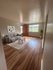 Inviting open-concept living room with elegant hardwood floors, modern gray sofa, and abundant natural light from large window.