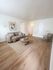 Bright and welcoming living room with a cozy beige sofa, stylish artwork, and modern wooden furniture on elegant hardwood flooring.
