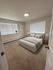 Inviting bedroom with cozy beige carpet, stylish bedding, and abundant natural light from large windows.