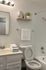 Modern bathroom with elegant lighting, a pristine white sink, and a stylish shelf displaying books and a plant.