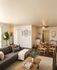 Cozy living room with a contemporary gray sofa, elegant wooden coffee table, and charming dining area in an open-concept apartment.