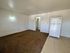 Bright and spacious room with modern white refrigerator, cozy carpet, and sleek tiled flooring leading into a welcoming interior.