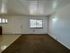 Bright living area with large window, crisp white walls, and plush carpet flooring, offering a cozy and inviting space.