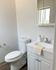 Modern bathroom with sleek white cabinetry, elegant sink, and hardwood flooring; features natural lighting through a small window.