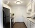 Bright and modern kitchen featuring sleek white cabinetry, dark appliances, and elegant countertops.