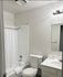Modern bathroom with elegant white fixtures, bathtub, and ambient lighting, providing a refreshing and inviting space.