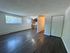 Inviting open-concept apartment with dark wood flooring, ample natural light, and a cozy kitchen area.