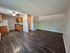 Bright, open-concept living area featuring elegant dark wood flooring and a modern kitchen with natural wood cabinetry.