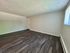 Spacious living area with elegant dark wood flooring and bright natural light.