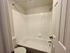 Bright and inviting bathroom featuring a classic white bathtub, elegant tiled walls, and a modern showerhead.