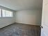 Bright and spacious bedroom with large window and plush carpet, perfect for relaxation and comfort.