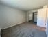Spacious bedroom with plush carpeting and a built-in closet, featuring a minimalist design with soft neutral walls.
