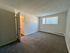 Spacious bedroom with plush carpet, inviting natural light through large window, and a half-open door providing a welcoming atmosphere.
