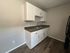Modern kitchen with sleek white cabinetry, dual sink, and elegant dark countertop, complemented by rich wood flooring.