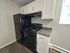 Modern kitchen with sleek black appliances, white cabinetry, and granite countertops.