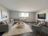 Bright and inviting living room featuring a contemporary sectional sofa, stylish armchair, and a sleek wall-mounted TV on beautiful wood flooring.
