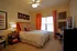 Inviting bedroom with elegant decor, featuring a plush bed, vibrant orange curtains, stylish artwork, and warm ambient lighting.