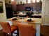 Inviting kitchen with dark wood cabinets, modern appliances, and chic decor, featuring a stylish island with orange striped chairs.