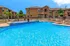 Inviting apartment complex featuring a sparkling pool surrounded by loungers and palm trees, perfect for relaxation.