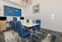 Modern dining area with elegant blue chairs, stylish chandelier, and unique dolphin wall art.