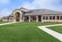 Charming single-story home with a modern design, surrounded by lush green lawns and featuring a welcoming front porch under a sleek metal roof.