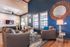 Elegant living room with plush seating, vibrant blue accent wall, large windows, and stylish decor.