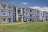 Elegant multi-story apartment complex featuring modern balconies, spacious lawns, and a charming exterior with stone accents.
