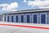 Modern apartment exterior with blue doors, showcasing a sleek design and pristine concrete pathway under a bright sky.